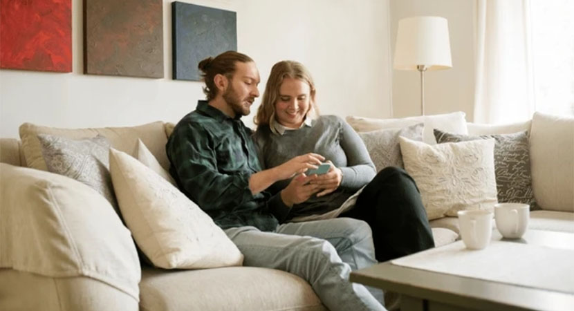 Couple Sitting on Couch looking at phone